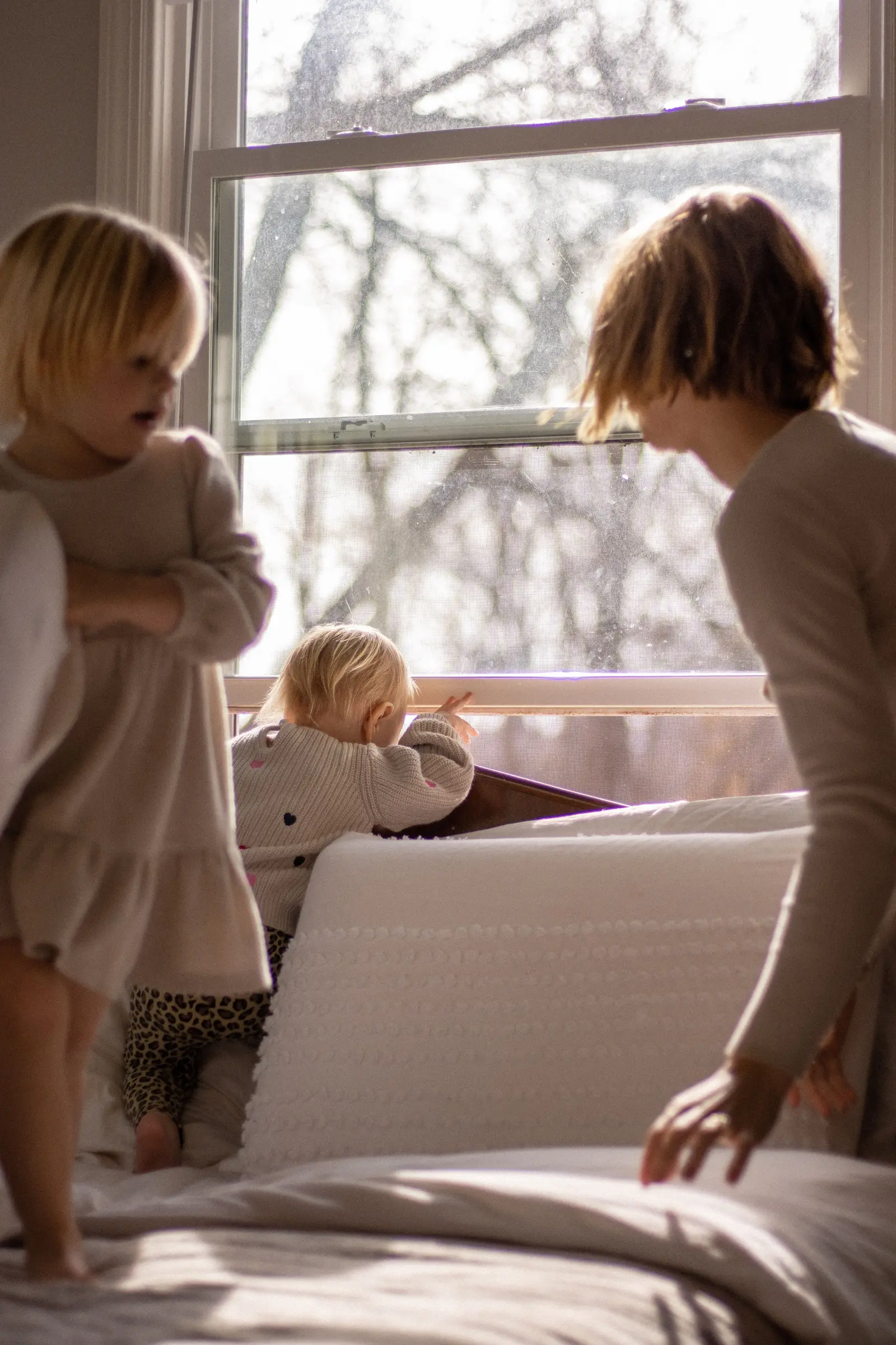Children and a caregiver spending time in a bright family room beside a large window